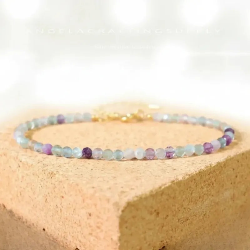 Multicolored beaded bracelet on a beige stone surface with a white background