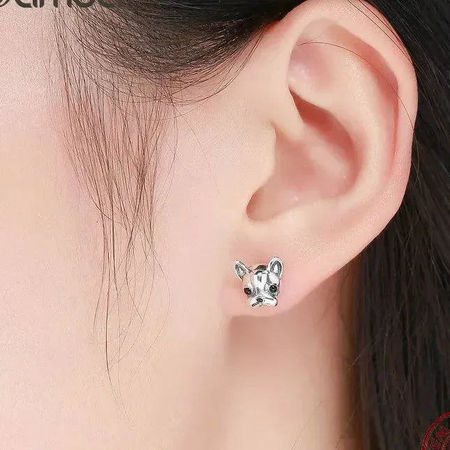 Silver dog-shaped earrings worn by a person with dark hair.