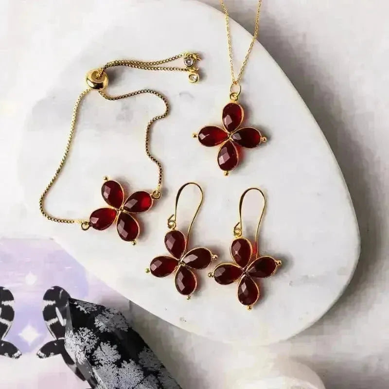 Butterfly-shaped jewelry set with red stones on a white stone surface