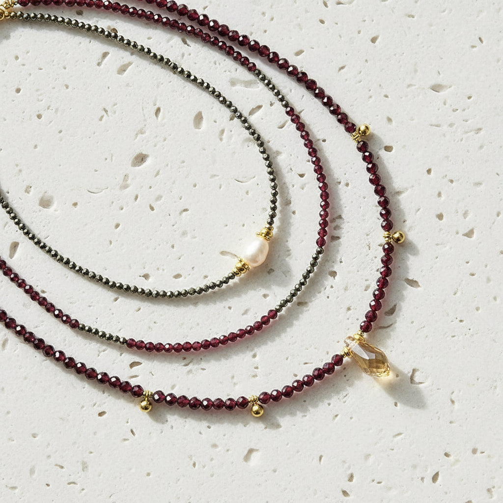 Three beaded necklaces with gold accents on a white background