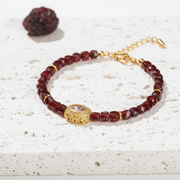 Garnet red and amethyst glass bead bracelet with gold-tone focal bead, full view