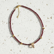 Necklace with red beads and gold accents on a gray background