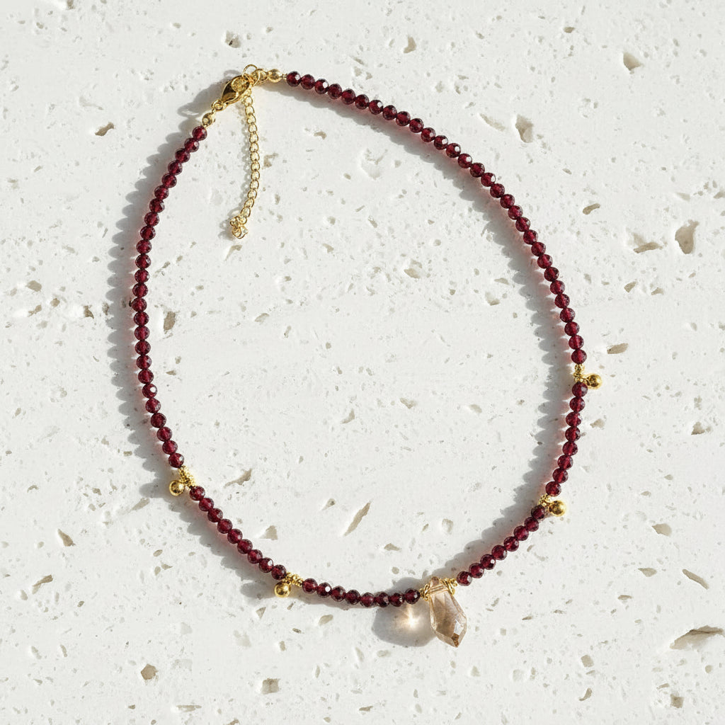 Necklace with red beads and gold accents on a gray background