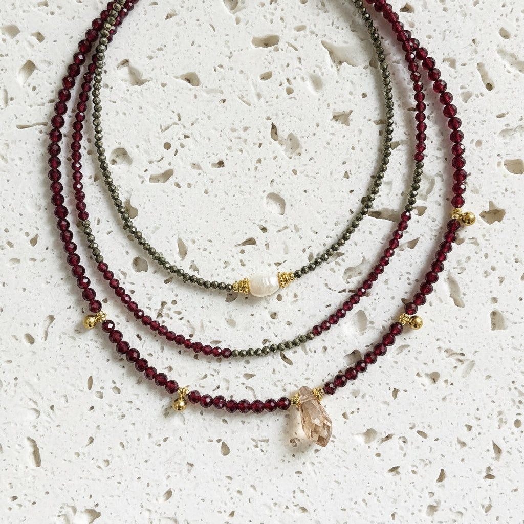 Three beaded necklaces with gold accents on a gray background