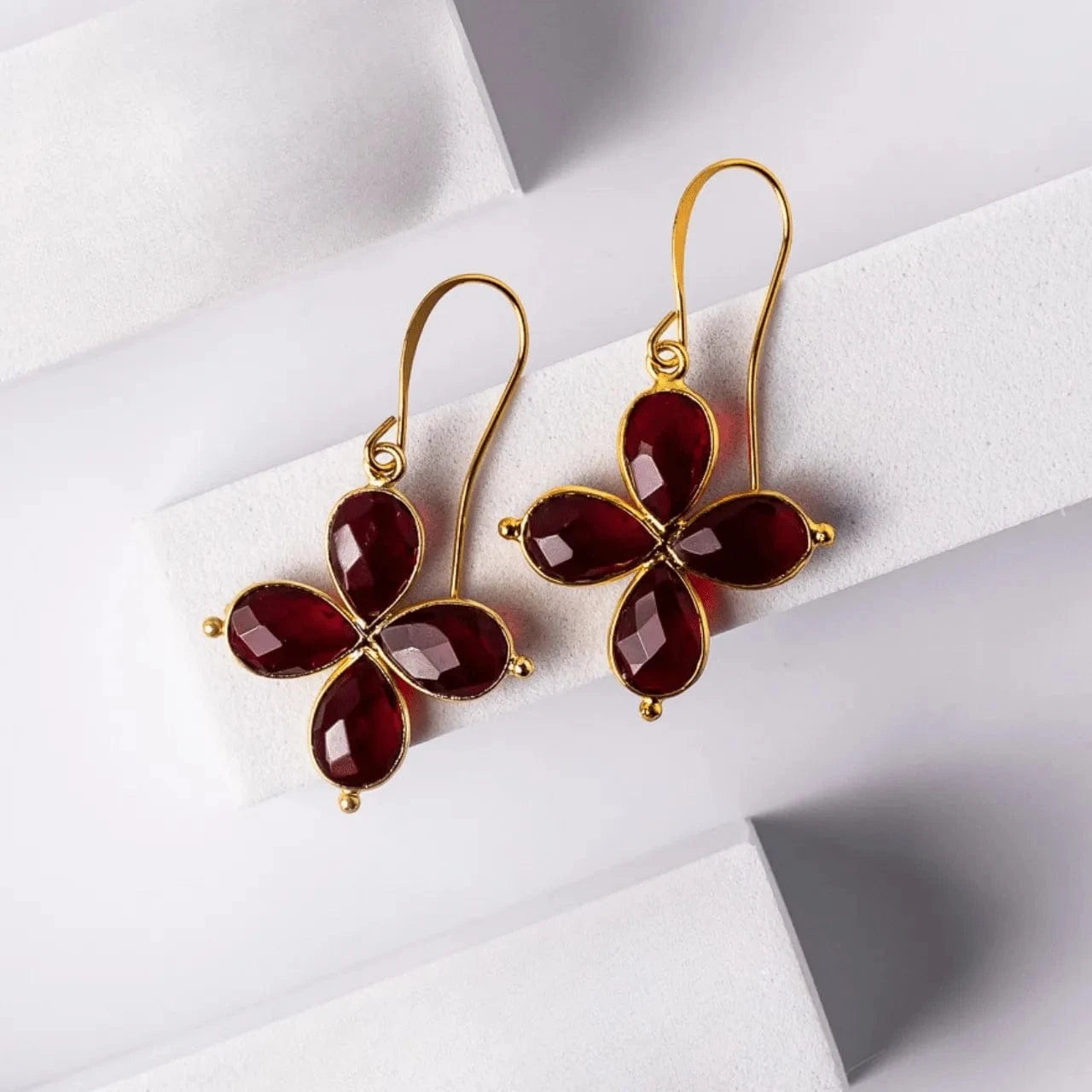 Gold earrings with red gemstones on a white background