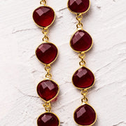 Gold earrings with red gemstones on a white marble surface