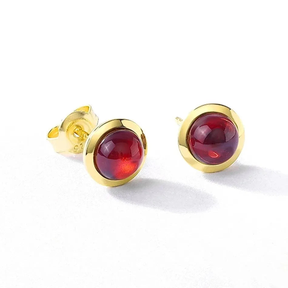 Gold earrings with red gemstones on a white background