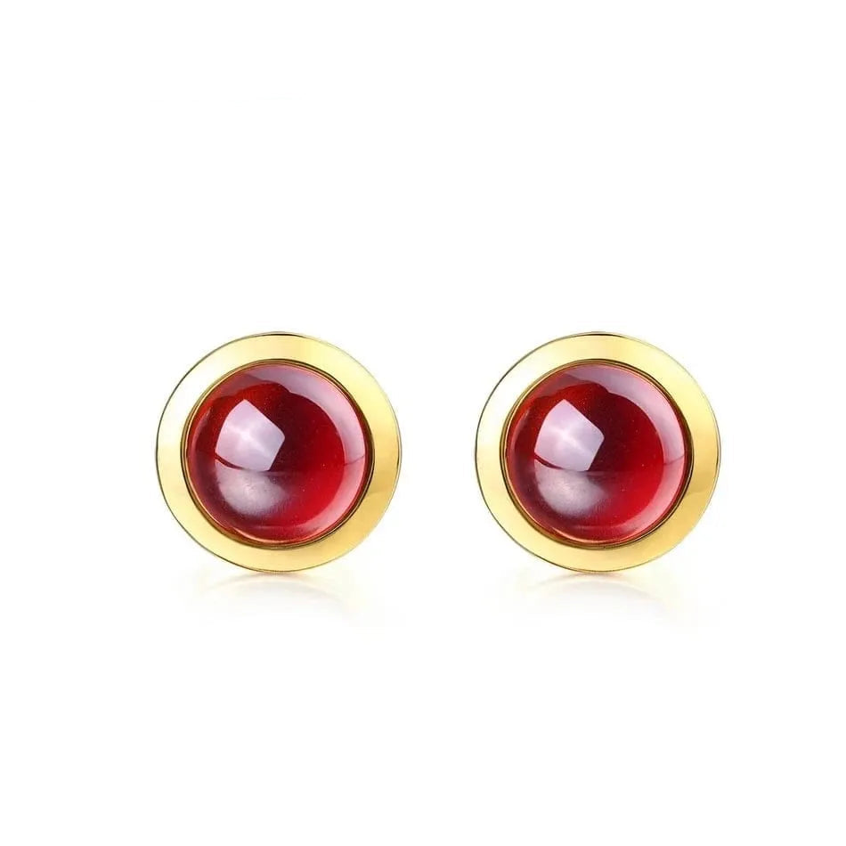 Gold earrings with red gemstones on a white background