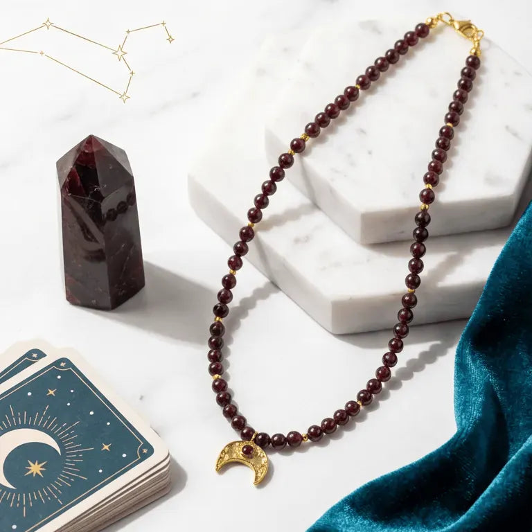 Garnet Moon Necklace on a white surface with cards and a crystal, featuring text about the necklace's symbolism and connection to the moon's cycles.