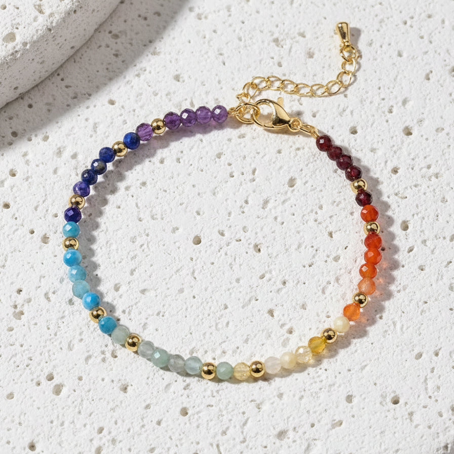 Multicolored beaded bracelet with gold accents on a white surface