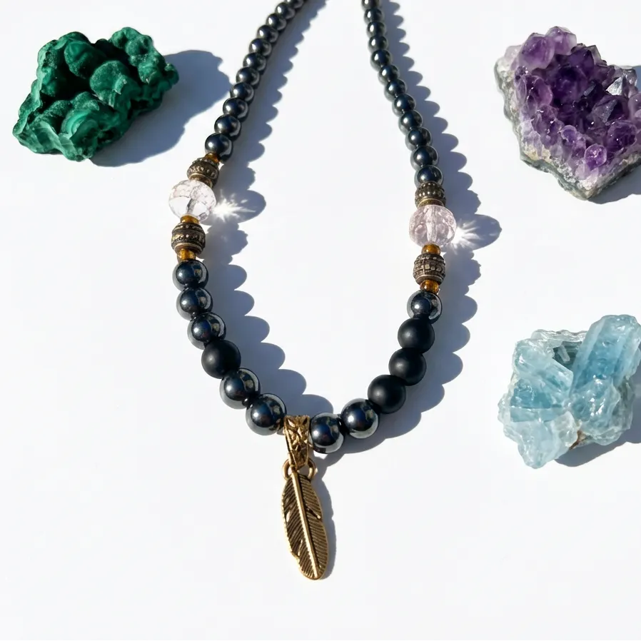 Necklace with black beads and a feather charm surrounded by crystals on a white background