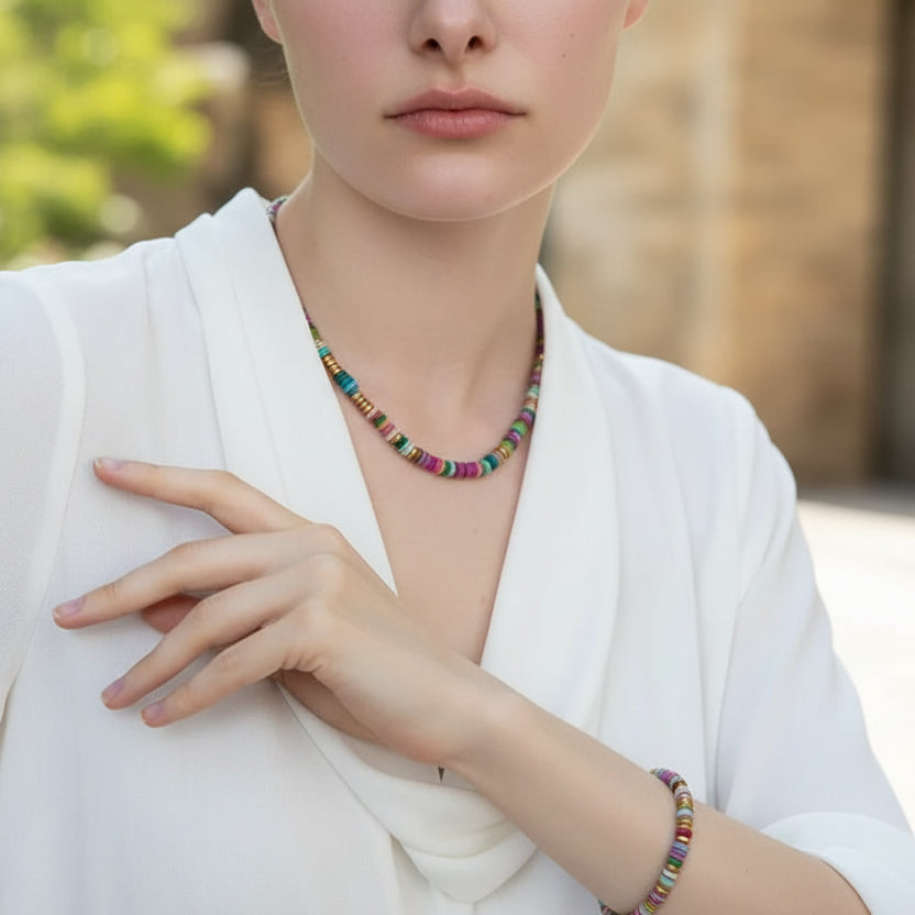 Woman wearing a dark blazer and colorful beaded necklace against a textured wall.