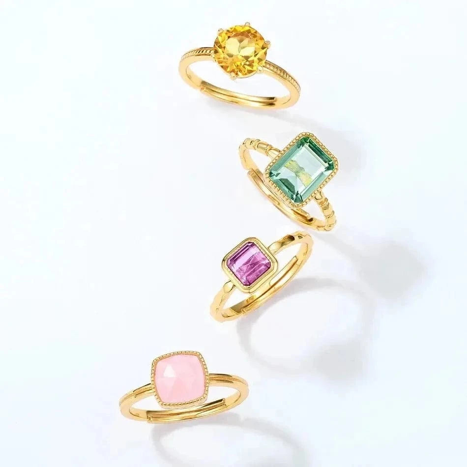 Set of four gold rings with colorful gemstones on a white background