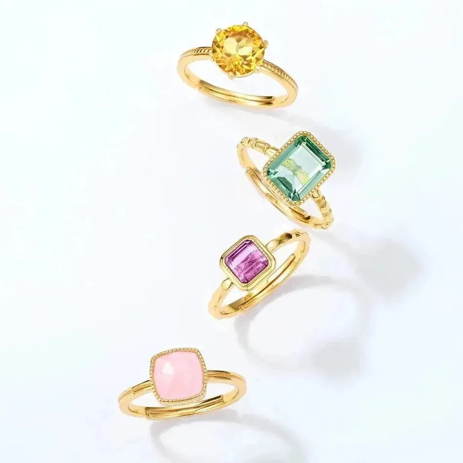 Set of four gold rings with colorful gemstones on a white background