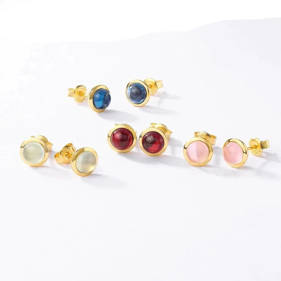 Set of gold earrings with colored gemstones on a white background