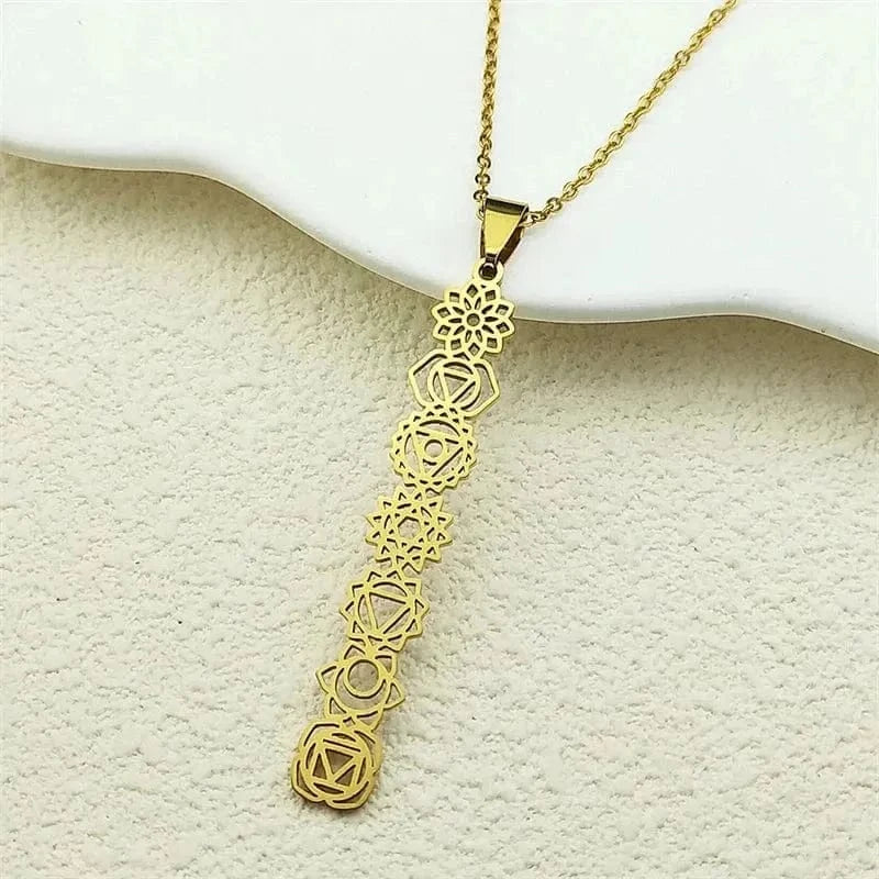 Gold necklace with a decorative pendant on a textured beige surface