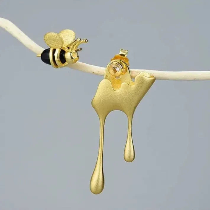 Gold honey dipper with a bee on a gray background