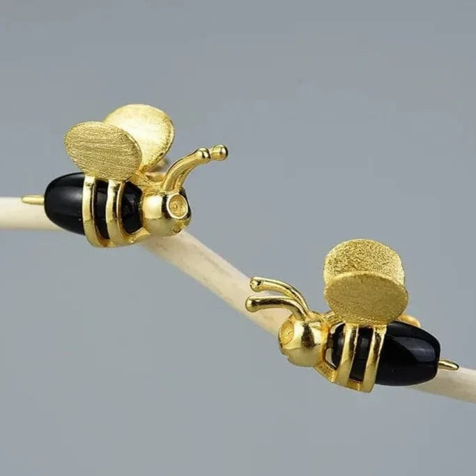 Gold bee-shaped earrings on a gray background