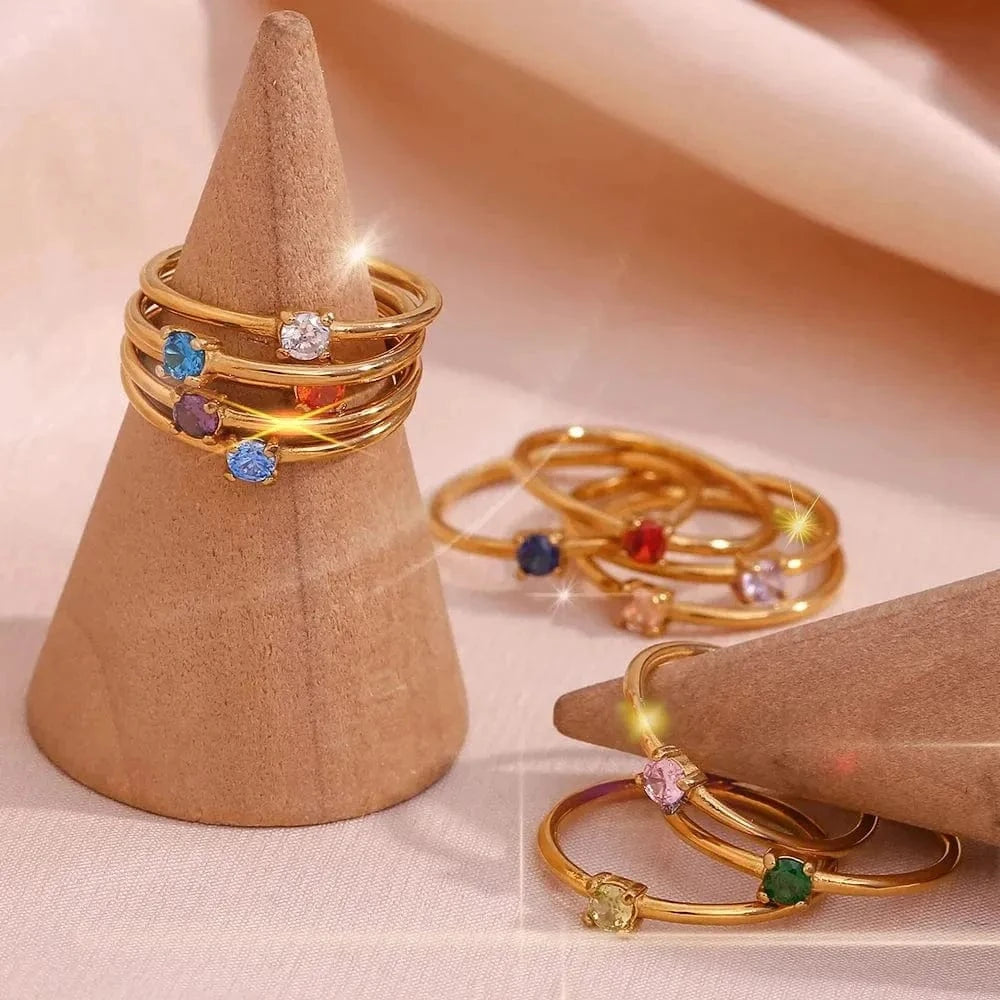 Gold rings with colorful gemstones on a cone-shaped jewelry stand.