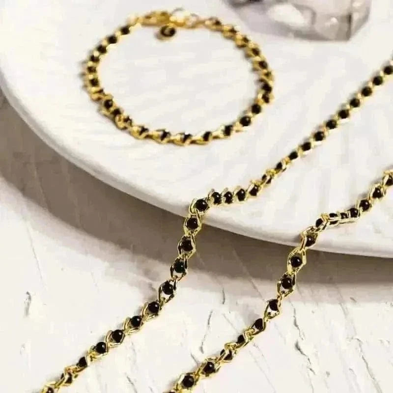 Gold chain with black stones on a white surface
