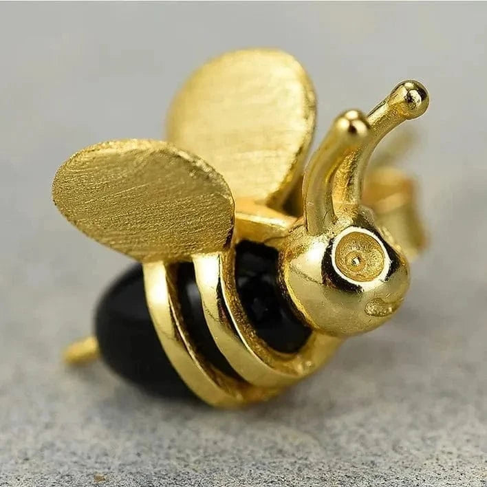 Gold bee-shaped earring on a gray background