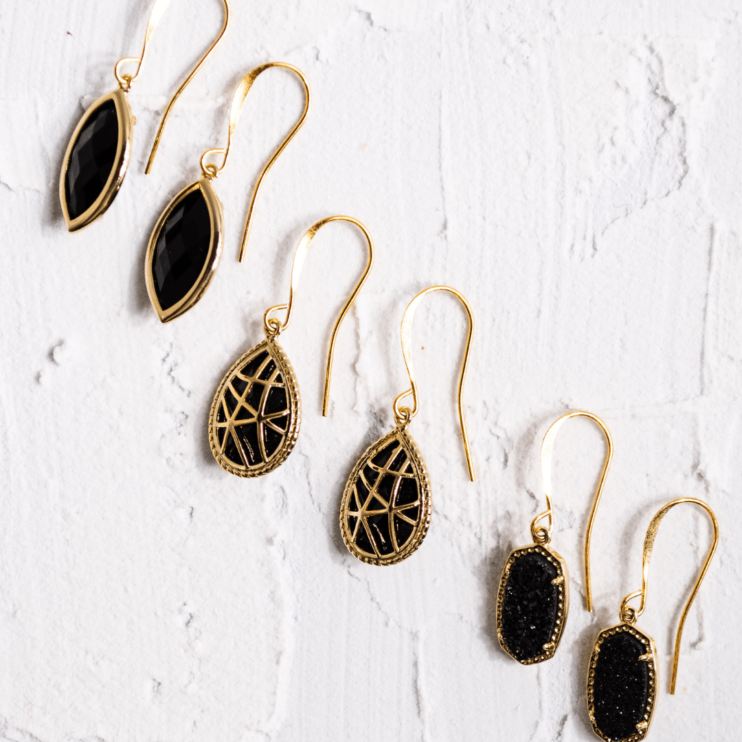 Gold earrings with black stones on a textured white surface