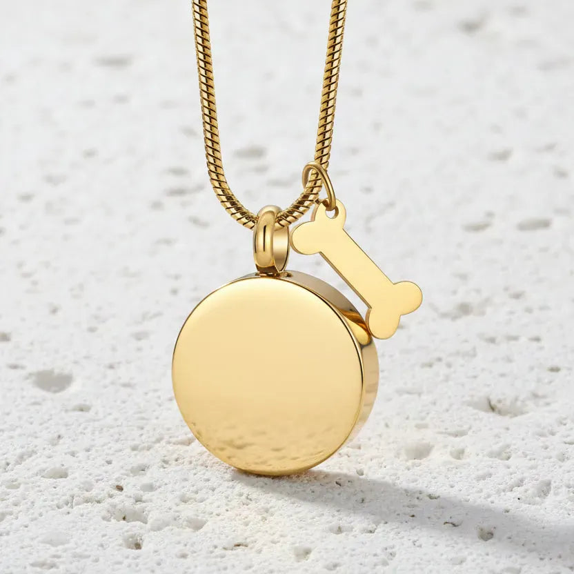 Gold necklace with a round pendant and a key-shaped charm on a white background
