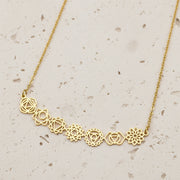 Gold necklace with floral designs on a black background