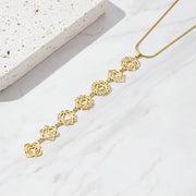 Gold chakra necklace with floral designs on a light surface