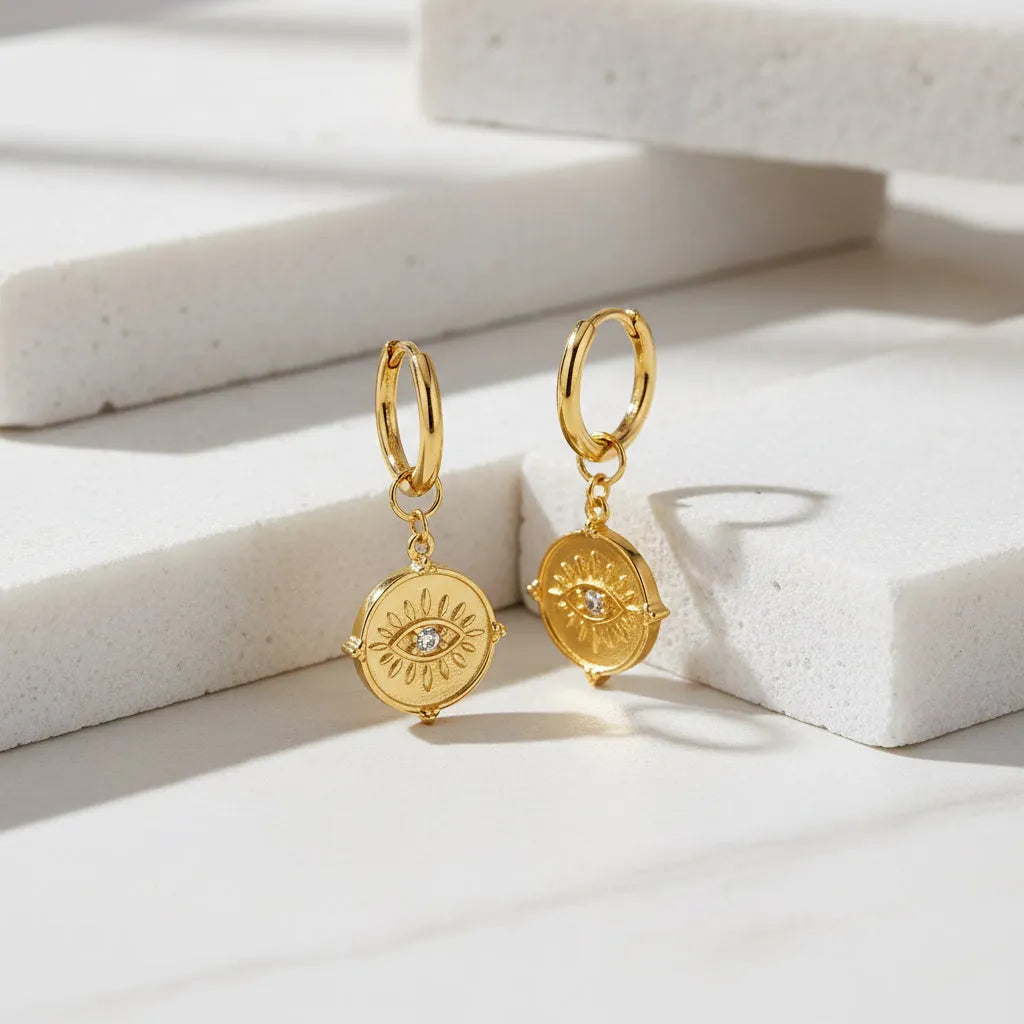 Gold earrings with circular designs and small diamonds on a white background