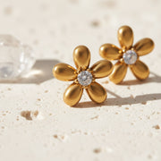 Close-up of gold flower stud earrings with cubic zirconia centre