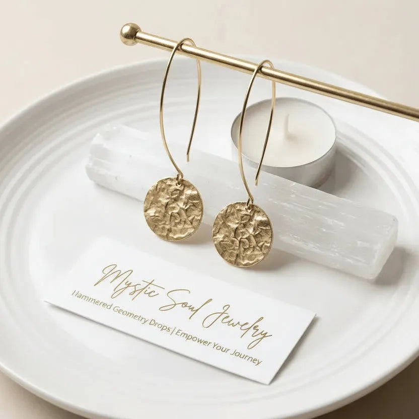 Gold earrings on a white plate with a candle and crystal, featuring 'Mystic Soul Jewelry' card.