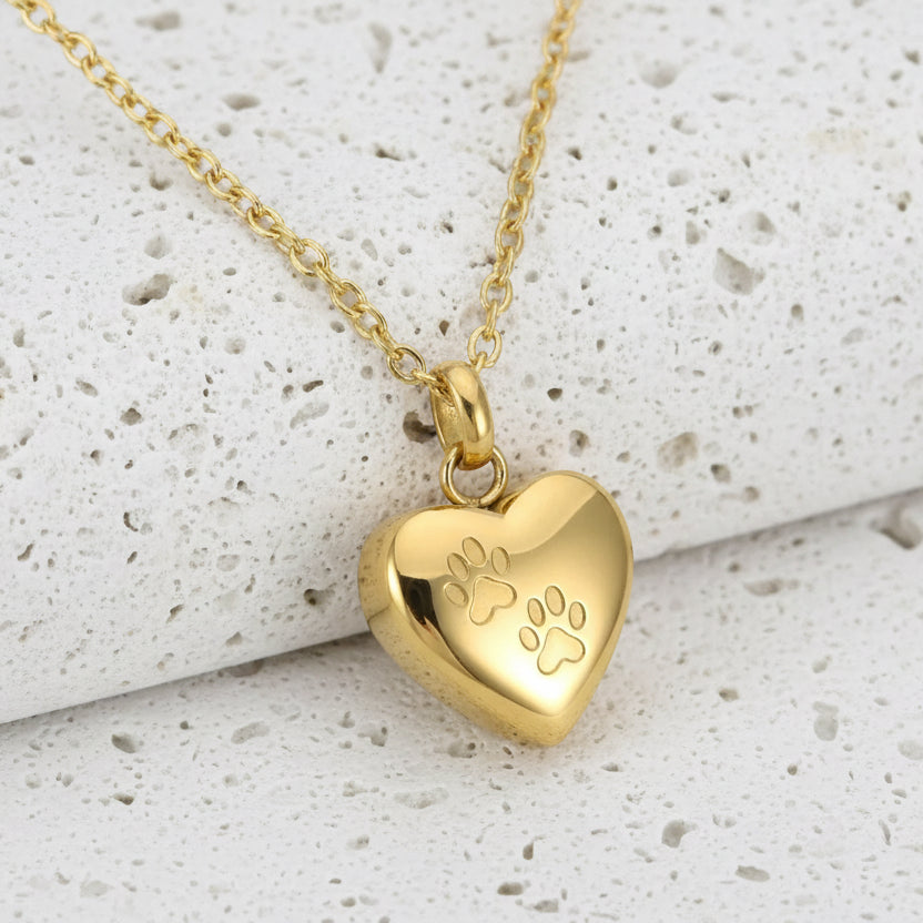Gold heart-shaped pendant with paw prints on a gold chain against a white background