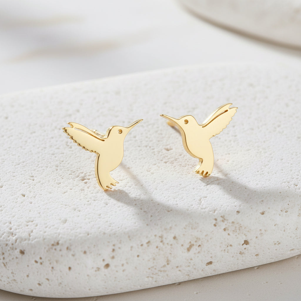 Gold hummingbird earrings on a white background