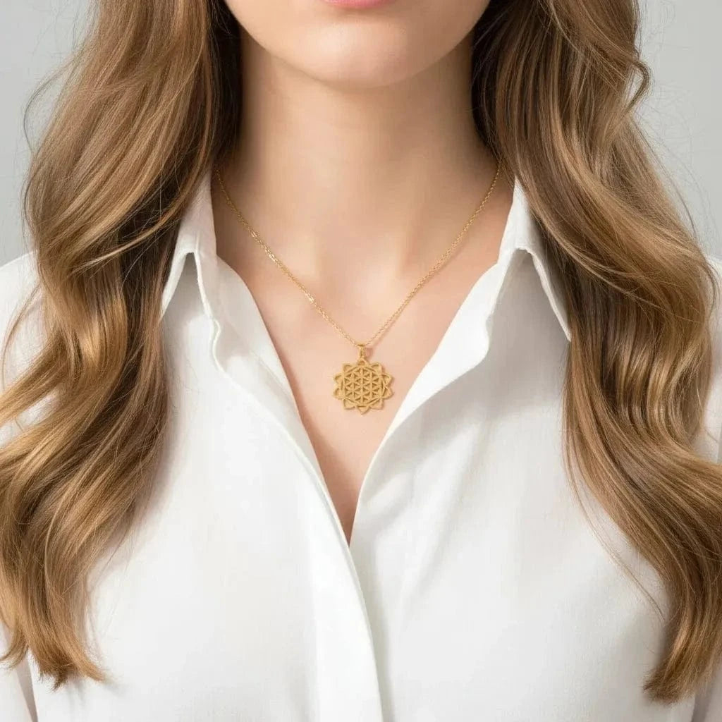 Gold necklace with a floral pendant worn by a person in a white top.