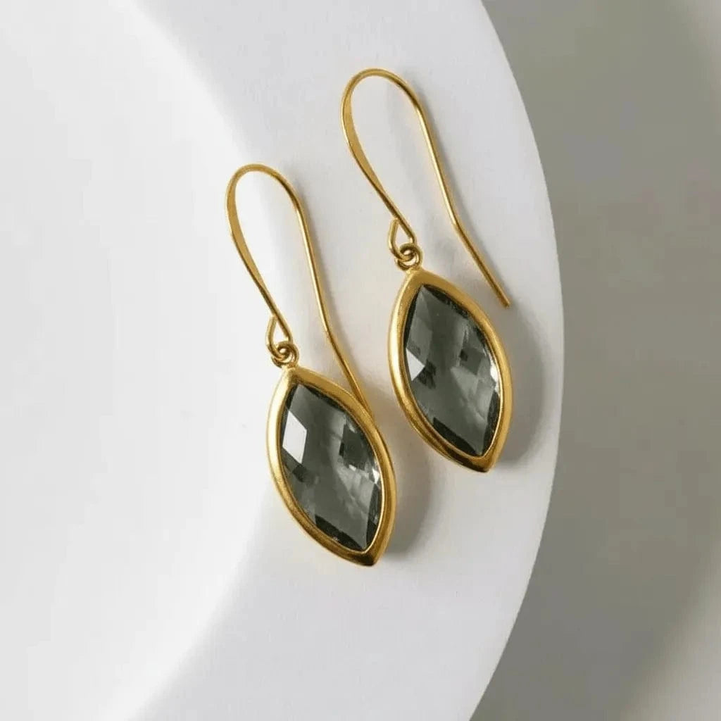 Gold earrings with green gemstones on a white background