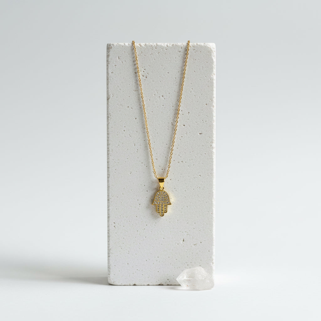 Mini gold hamsa hand necklace with crystal centre on a white display block