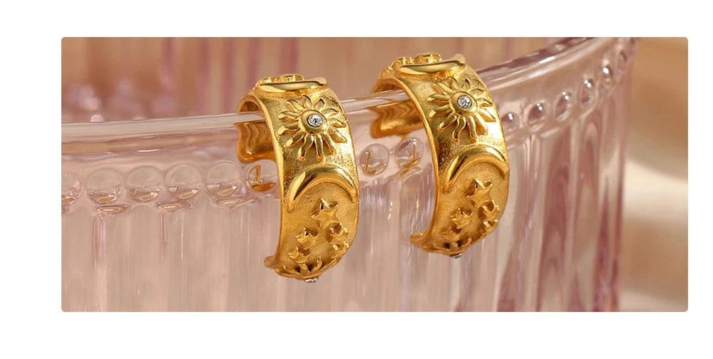 Gold hoop earrings on a clear glass surface