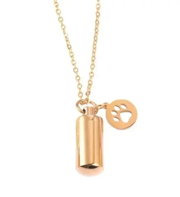 Gold necklace with a cylindrical pendant and heart-shaped tag on a white background