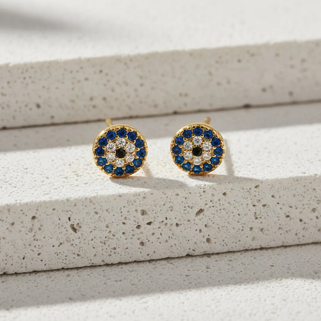 Pair of gold earrings with blue and black gemstones on a white background