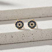 Pair of gold earrings with blue and black gemstones on a white background