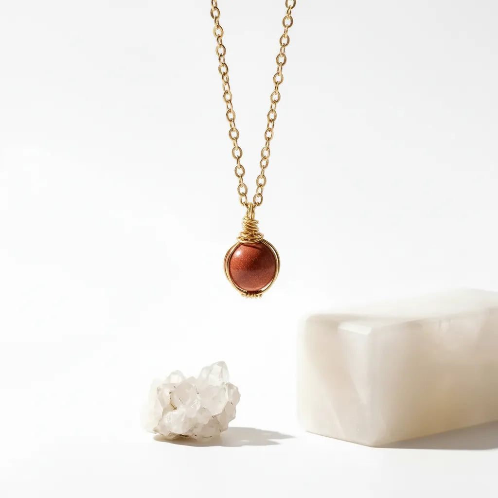 Gold necklace with a red pendant on a white background
