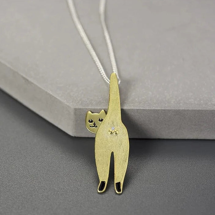 Gold cat-shaped pendant on a gray surface
