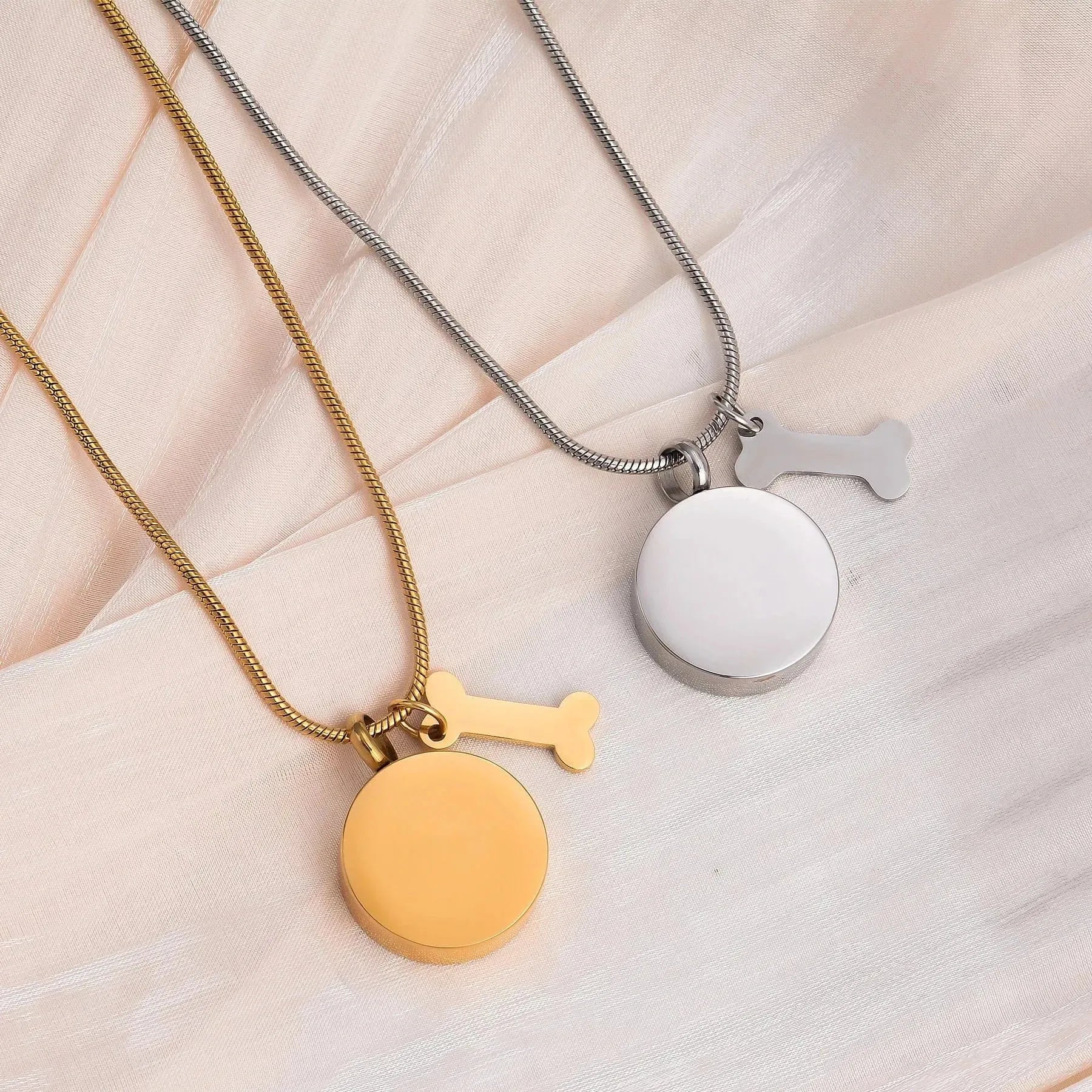 Two necklaces with round pendants on a light fabric background