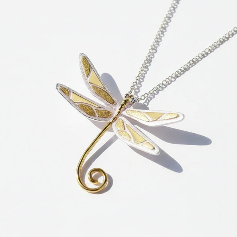 Dragonfly-shaped pendant on a chain against a dark background
