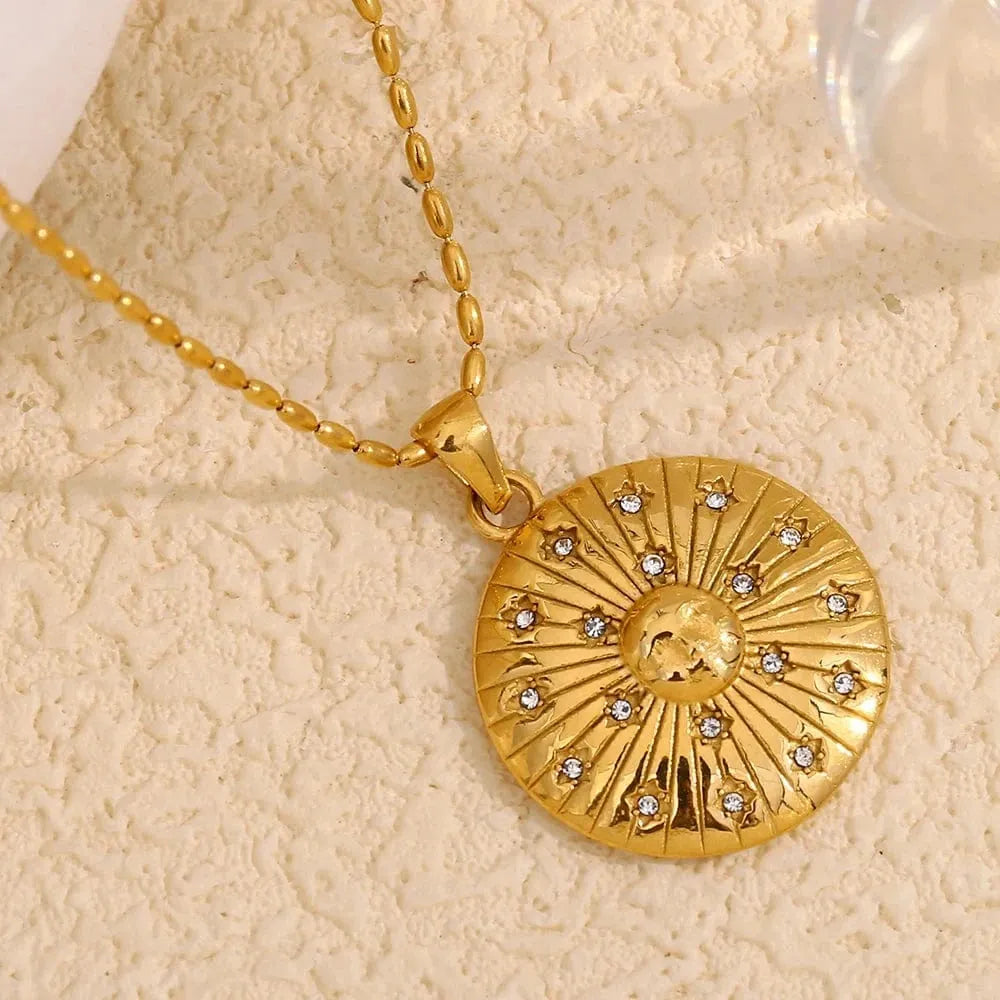 Gold necklace with a circular pendant featuring a sun design on a beige background