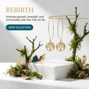 Gold tree-shaped earrings on a decorative stand with natural elements and 'Rebirth' text.
