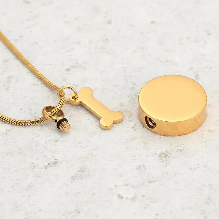 Gold necklace with a bone-shaped pendant on a white background