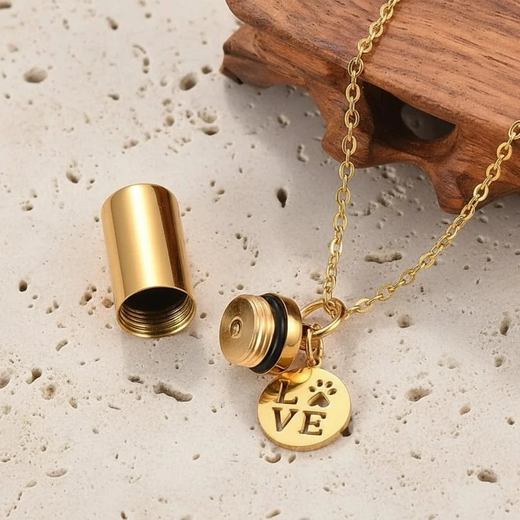 Gold necklace with a cylindrical pendant and 'LOVE' charm on a dark background