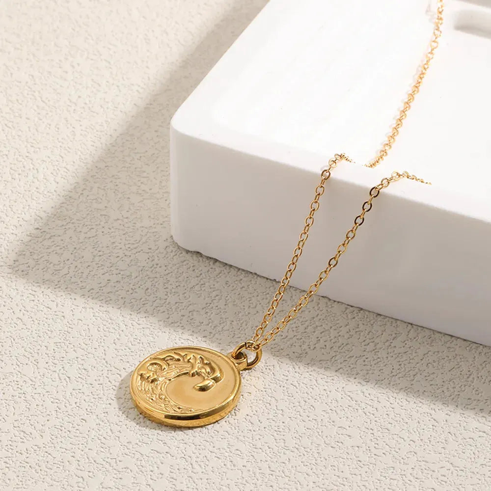 Gold necklace with a round pendant on a light surface